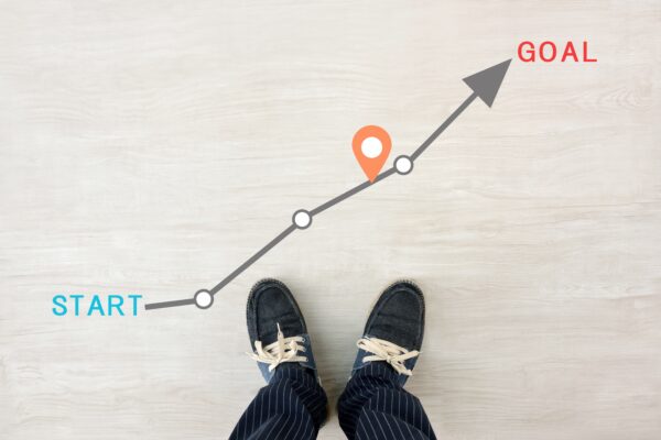 A man standing at the start of a drawn path labeled “start" and "goal,” symbolizing a career map.